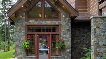 A stone building with a red door, large windows, and a stone staircase leading up to a balcony.