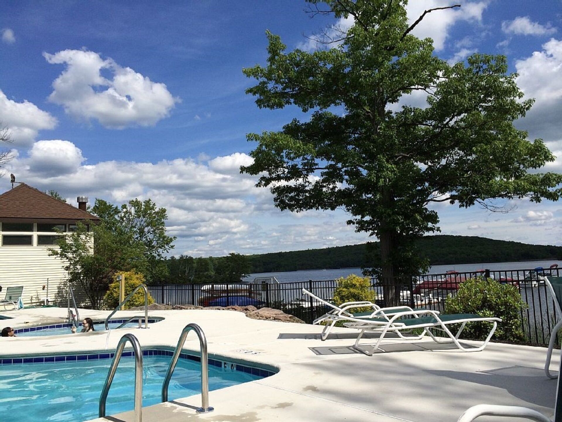 Ein Schwimmbecken mit Blick auf einen See und Hügel im Hintergrund.