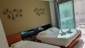 Een hotelkamer met twee bedden, een groot raam met gordijnen en decoratie aan de muur.
