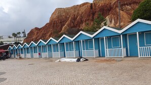 Een rij blauwe vakhuizen met witte reling, genummerd op volgorde, voor een rotsachtige klif.