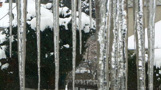 Ett snötäckt utomhusområde med bänkar och istappar som hänger ner från taket.