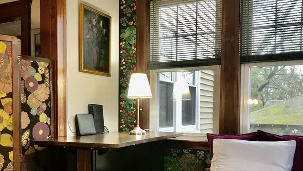 A bedroom with a bed, desk, and chair. There is a window with blinds, a lamp, and a painting on the wall. - JACARANDA.  A comfortable, secure two-story colonial.  Whole house.  (Milton)