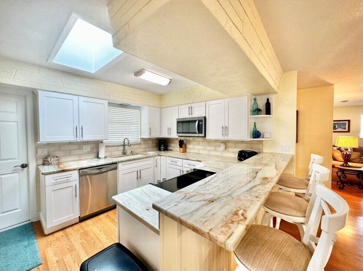 A modern kitchen with white cabinetry, a large island, and a skylight.