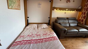 Een kamer met een bed, een leren bank, een kaart aan de muur en een houten plafond.