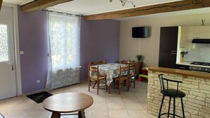 Un comedor con mesa y sillas, una cocina con estufa y alacenas, y una ventana con cortina.