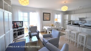A living room with a television, seating, and a kitchen area. - New 2010 - 1 bdrm penthouse, ocean front, south and north facing terrace, luxury (Garachico)