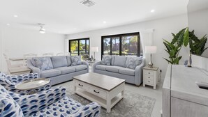 A modern living room with a sofa set, a coffee table, and a dining table.