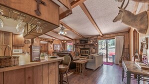 Ein rustikales Blockhaus mit Holzwänden, einem Kamin aus Stein, einem Essbereich und einer Bar mit einer Weinkühllage.