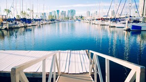 A marina with boats docked, a wooden pier, and a city skyline in the background. - Ocean & Fireworks Views Condo at the Ilikai Hotel w/Full Kitchen & Free WiFi (Honolulu)