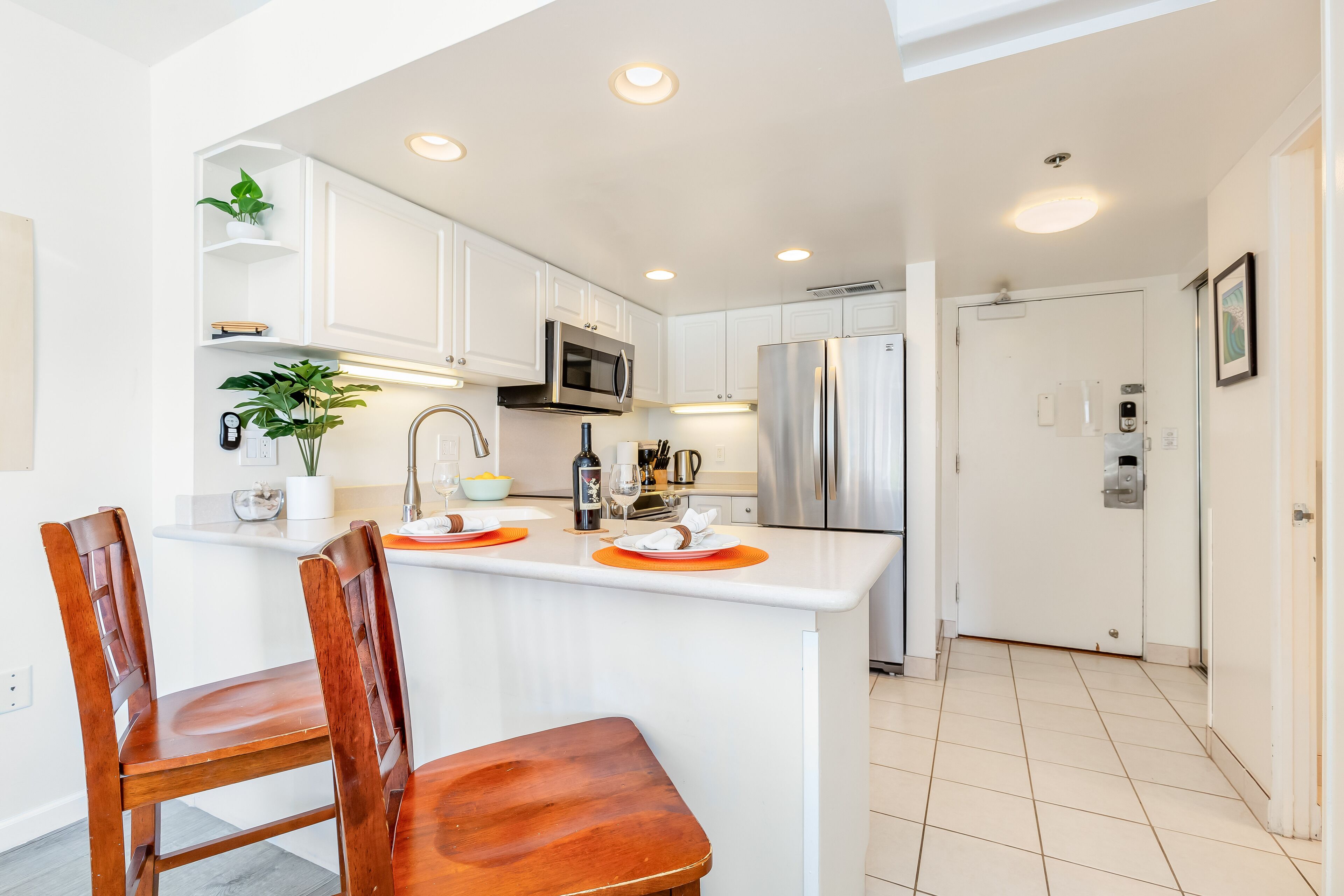 A modern kitchen with white cabinetry, stainless steel appliances, and a wooden dining area.