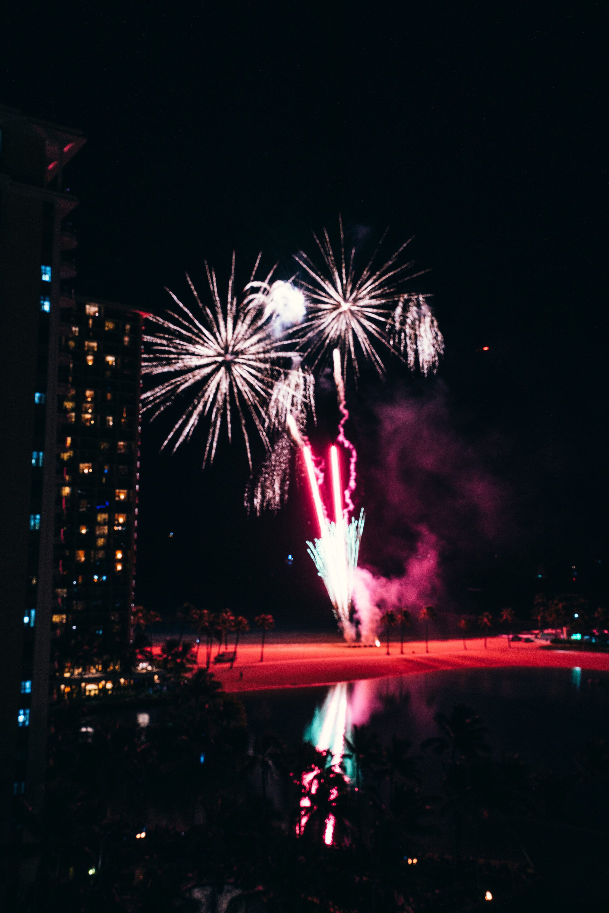 Vista noturna de fogos de artifício sobre uma paisagem urbana com edifícios altos.