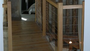 A wooden staircase with a metal railing, leading to a room with a bed and a lamp. - Les Lattis: Cottage restored in the traditions, in a typical farm of Vexin (Avernes)