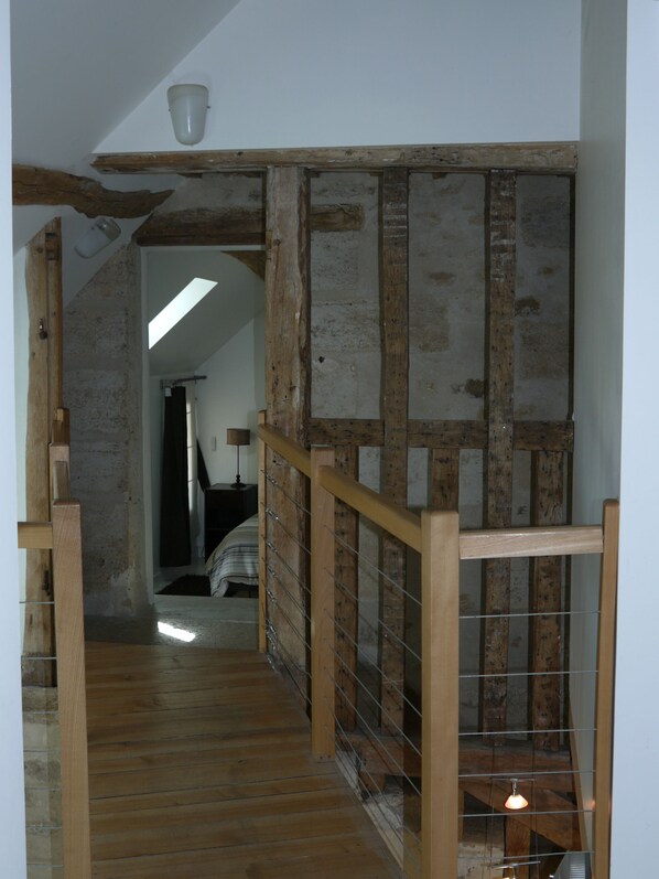 A wooden staircase with a metal railing, leading to a room with a bed and a lamp. - Les Lattis: Cottage restored in the traditions, in a typical farm of Vexin (Avernes)