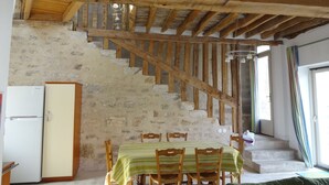 A rustic interior with a wooden staircase, a dining table with chairs, and a refrigerator. - Les Lattis: Cottage restored in the traditions, in a typical farm of Vexin (Avernes)