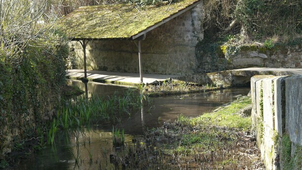 A rustic stone building with a moss-covered roof, situated beside a calm waterway with a small bridge. - Les Lattis: Cottage restored in the traditions, in a typical farm of Vexin (Avernes)