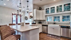 A kitchen with white cabinets, a central island, wicker chairs, and pendant lighting. - Gulf Views-Private Heated Pool-5 bikes included! (Santa Rosa Beach)