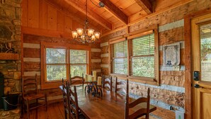 A rustic wooden dining room with a chandelier, large windows, and a stone fireplace. - Million $ View: Hot Tub | Theater Room | Pool Table | Air Hockey | 10min to Banner Elk (Banner Elk)