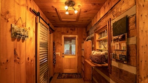 A wooden cabin interior with a door, a window, a shelf with glassware, and a welcome sign. - Million $ View: Hot Tub | Theater Room | Pool Table | Air Hockey | 10min to Banner Elk (Banner Elk)