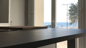 Una habitación con un ventanal grande, una puerta y una mesa con taburetes.