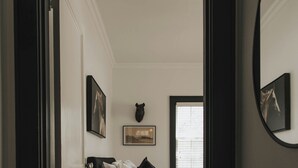 Un dormitorio con cama, ventana y espejo.