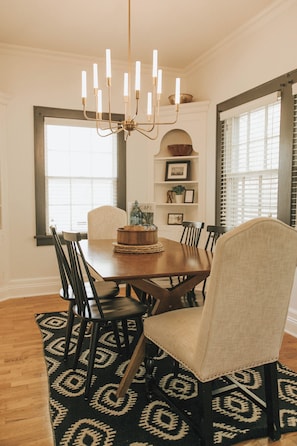 Un coin repas comprenant une table en bois, six chaises, un lustre et un tapis à motifs.