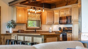 A kitchen with wooden cabinets, a built-in stove, and hanging pendant lights. - Red Rock Vista Cabin-Fall Family Vacation in Jasper (Jasper)