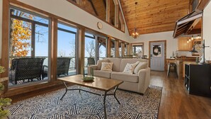 A spacious living area with a large window, a sofa, a coffee table, and a patterned rug. - Red Rock Vista Cabin-Fall Family Vacation in Jasper (Jasper)
