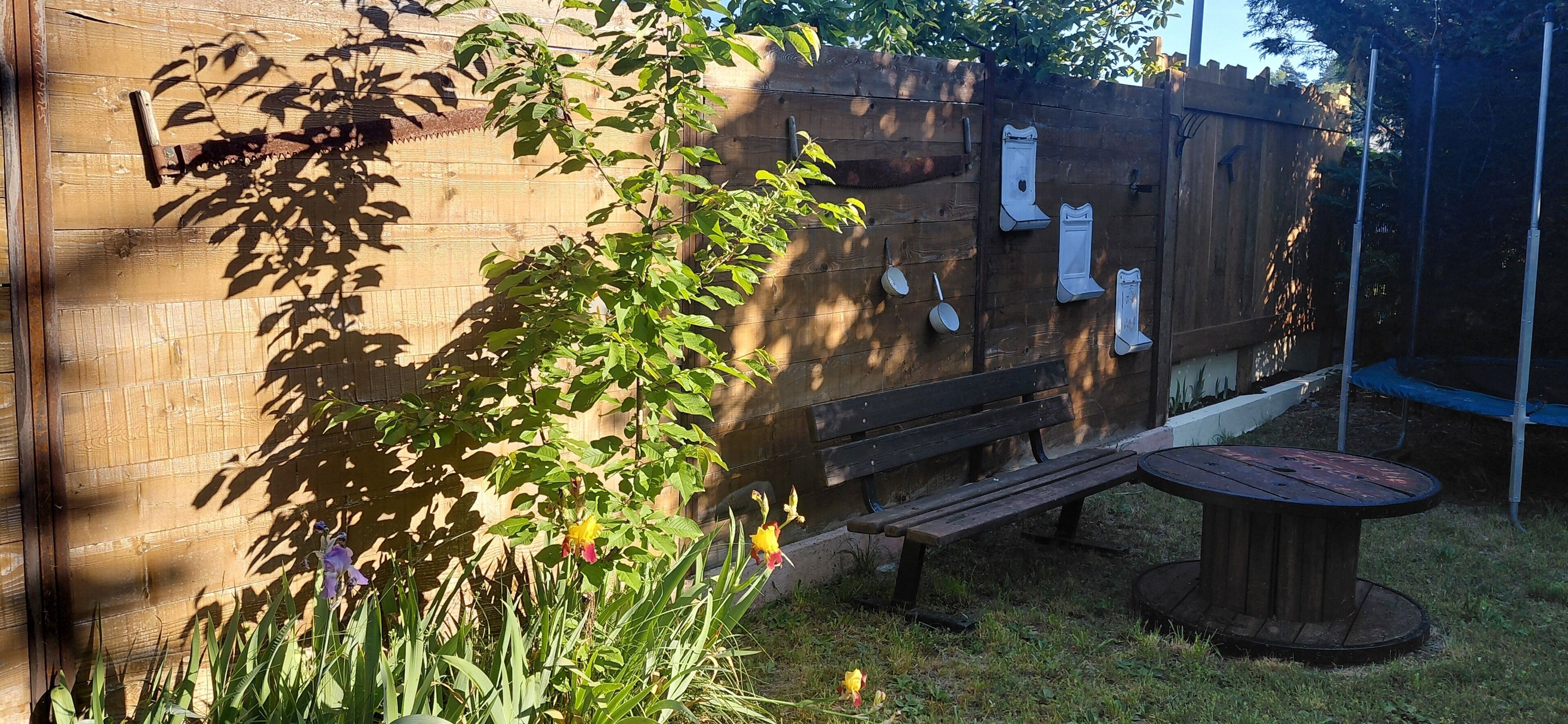 A wooden fence, a bench, and a table in a garden area.