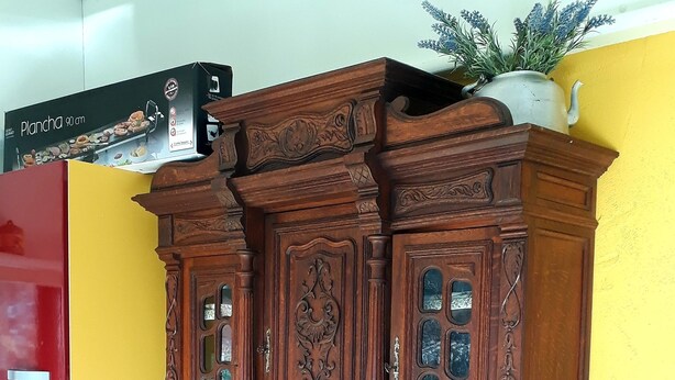 A wooden cabinet with intricate carvings and multiple compartments, placed against a yellow wall. - Wunderful and cosy house in the heart of the canyon Verdon (Castellane)