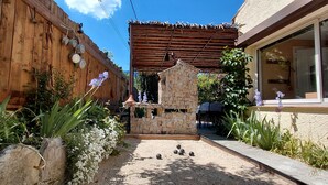 A courtyard with a stone structure, a wooden fence, and a covered area with a table and chairs. - Wunderful and cosy house in the heart of the canyon Verdon (Castellane)