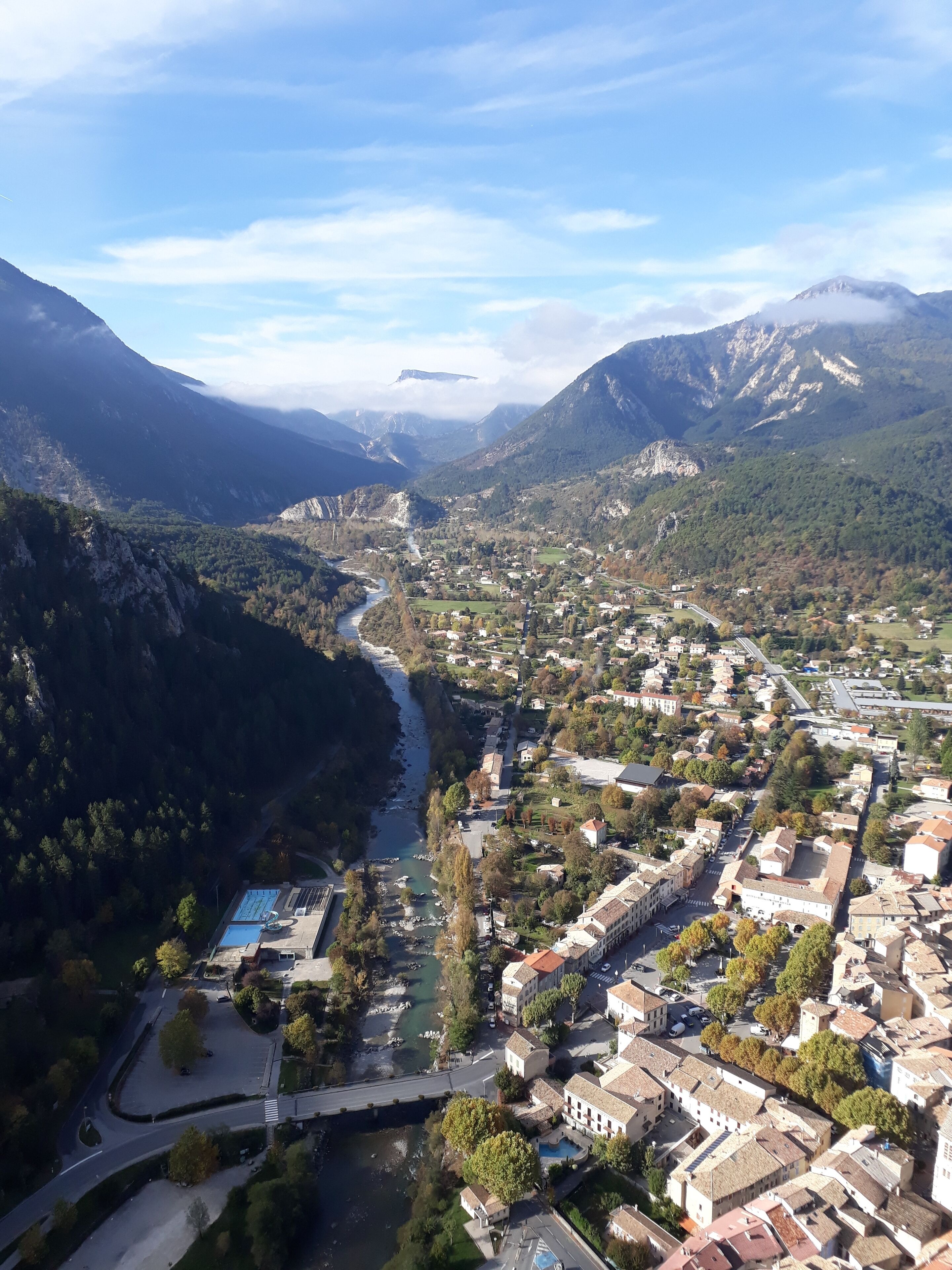 An aerial view of a town with a river running through it, surrounded by mountains.