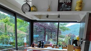 A modern kitchen with a yellow countertop, two wooden chairs, a clock, and a 'MOTOS' sign. - Wunderful and cosy house in the heart of the canyon Verdon (Castellane)