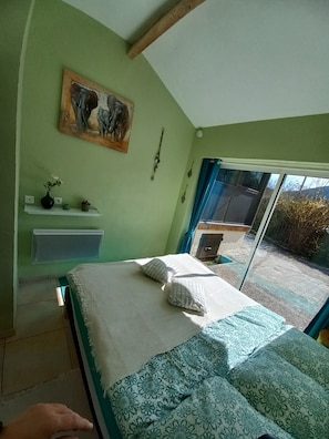 Ein Schlafzimmer mit Bett, Kissen, einem Gemälde, einer Ablage mit Dekoration und einem Fenster mit Blick.
