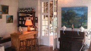 Una habitación acogedora con una barra de madera, una estantería, un piano y un cuadro grande de un paisaje.