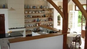 Una cocina con vigas de madera, salpicadero de azulejos blancos y estantes con utensilios de cocina.