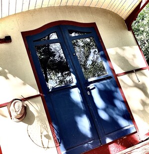 Eine blaue Tür mit Glasfeldern, eingebaut in ein Gebäude mit einer gewölbten Dachkonstruktion und einer weißen Fassade.