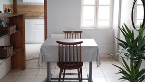 Et spiseområde med et bord og stole, en hængende lampe, et vindue med udsigt og en potteplante.