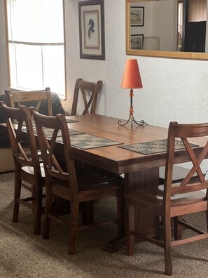 A dining table with six wooden chairs, a woven placemat, and a decorative table lamp.