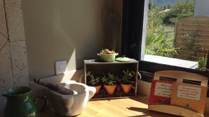 A wooden table with a green pitcher, a mortar and pestle, a wooden cutting board, and a small potted plant.