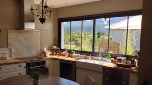A modern kitchen with a large window, a dining table, and various kitchen appliances.