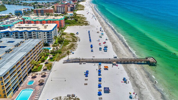 An aerial view of a coastal hotel with a beach, a pier, and a pool area. - Beach Cottages Beachfront - Your Escape Awaits!   Sun, Secure, Family Friendly  (Indian Shores)