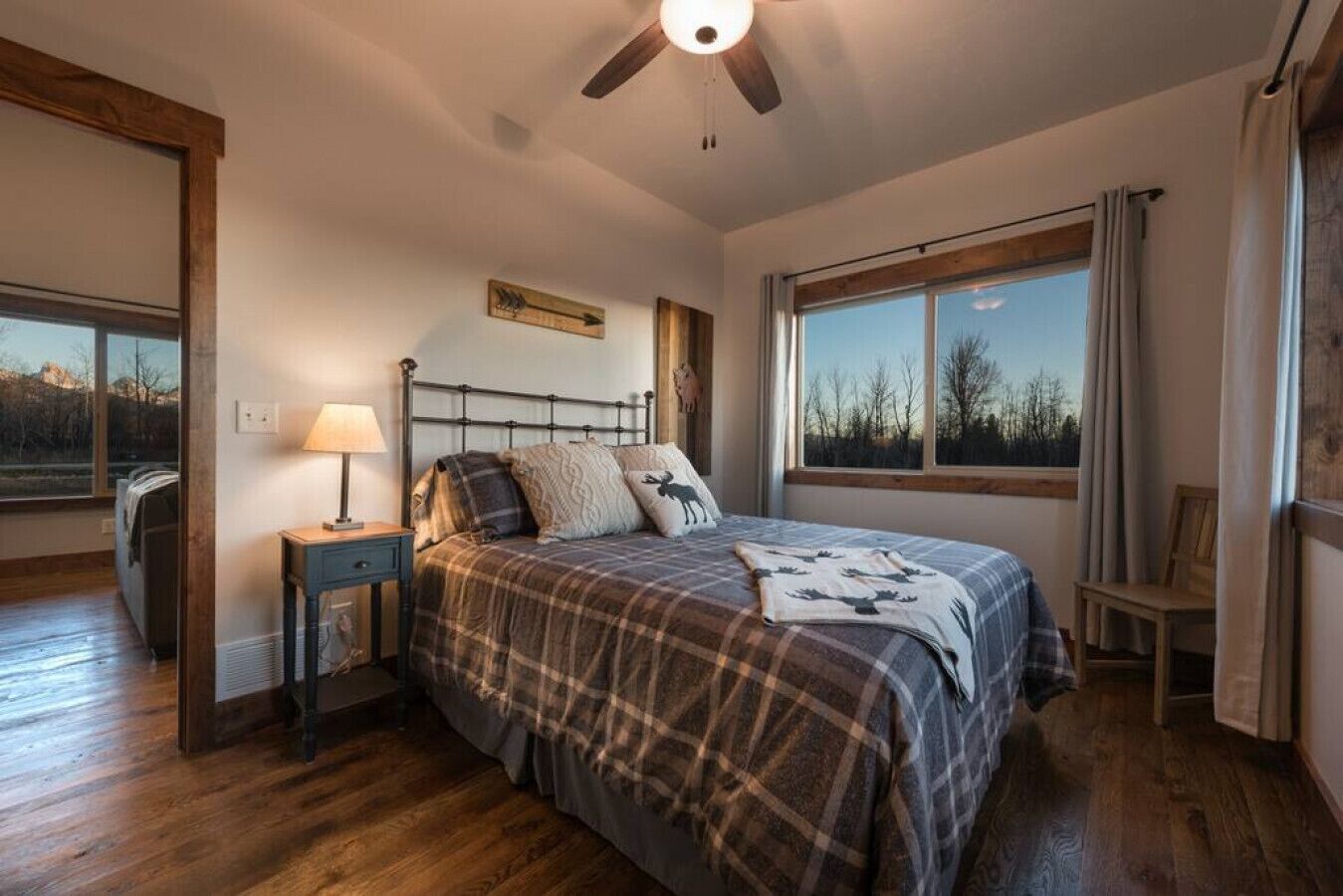A bedroom with a bed, a nightstand, a lamp, a window, and a ceiling fan.