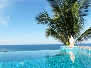 An infinity pool with clear blue water, a palm tree, and a view of the ocean. - Luxury apartment 150 m from the sea Cathy Home D6 (Bophut - Koh Samui)