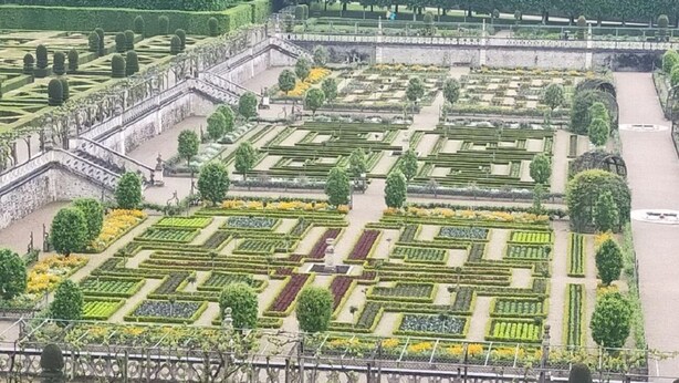 Un jardin à la française, avec des allées symétriques et des haies soigneusement taillées.