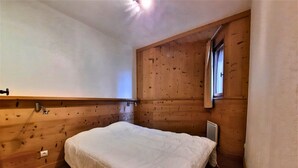 A bedroom with a wooden sloped ceiling, a single bed, a window, and a radiator. - Classic apartment 6 ppl, pets allowed, Les Menuires (Les Menuires)