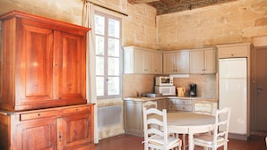 Una cocina con armarios de madera, una mesa blanca y sillas.