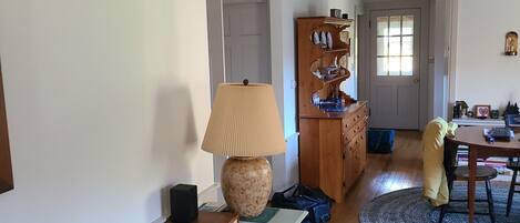 A cozy living room with a sofa, a lamp, a wooden cabinet, and a dining area with a table and chairs.