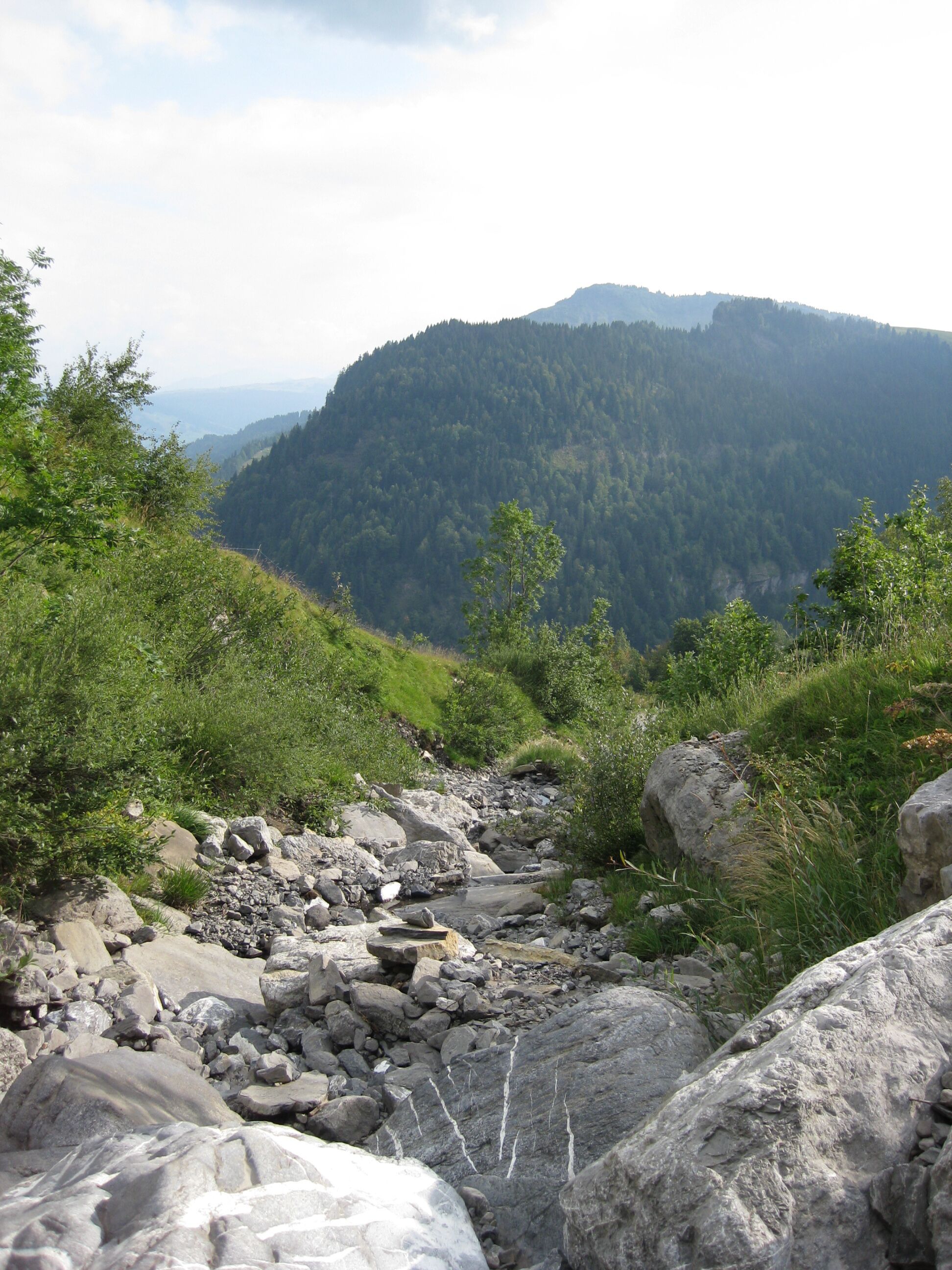 Un ruisseau aux rives rocheuses, avec une chaîne de montagnes en arrière-plan.