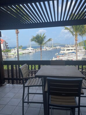 A covered outdoor seating area with a view of a marina and boats.