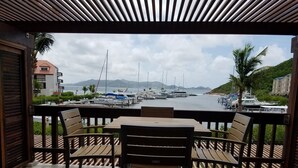 A covered outdoor seating area with a view of a marina and boats. - Welcome to Paradise! (St Thomas)